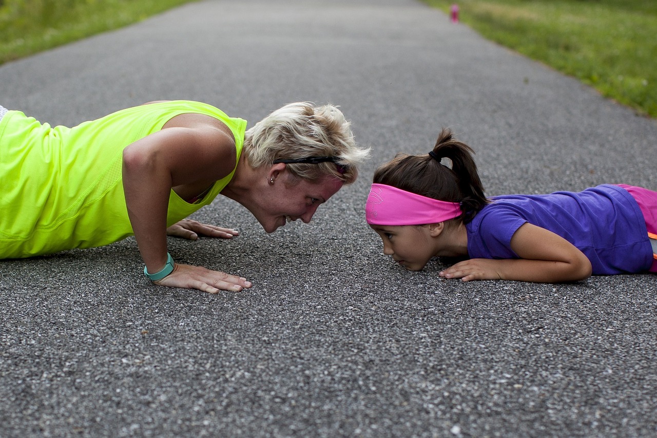 Mother and daughter doing pushups on concrete