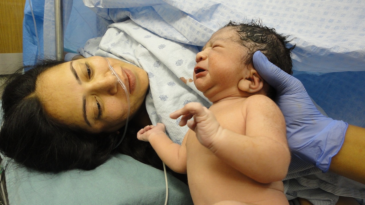 Newborn baby being handed to mother after birth