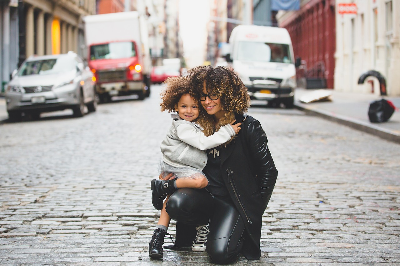 Single mother hugging daughter in the street