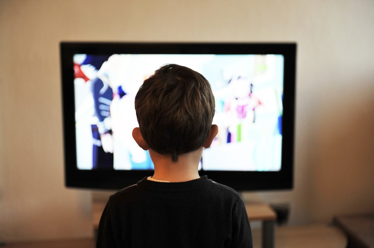 Young boy sitting in front of television screen